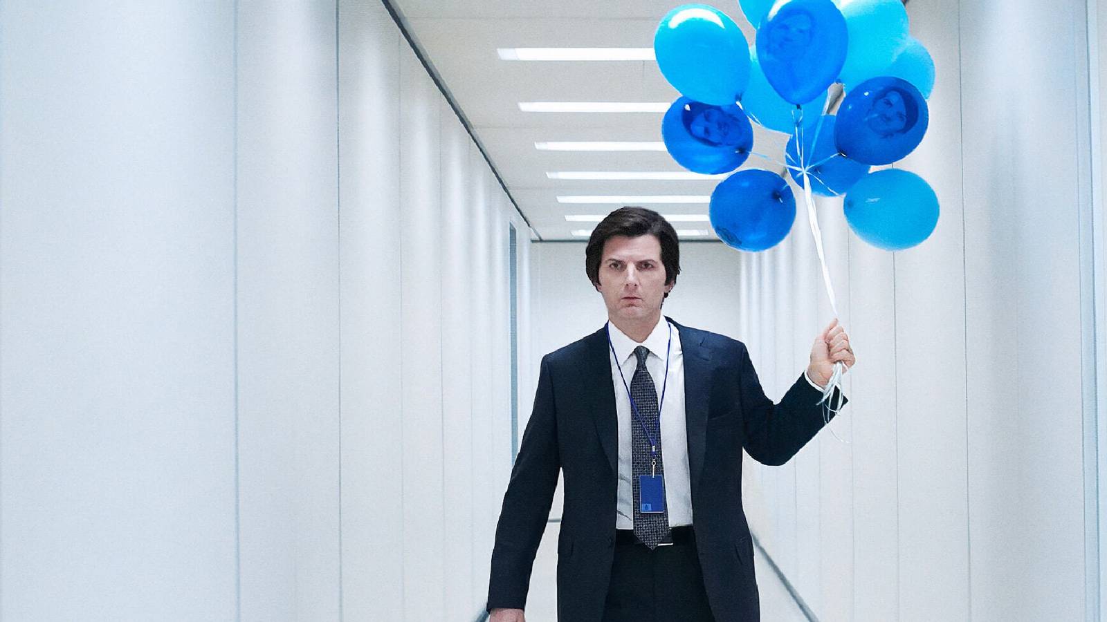 Mark (Adam Scott) holding a string of blue balloons in a white hallway in Severance