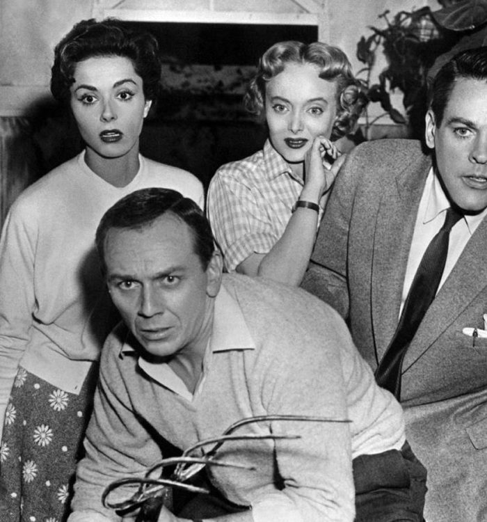 The cast of Invasion of the Body Snatchers look at something in horror while standing in a greenh...